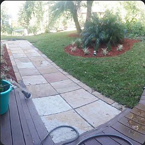 Flagstone walkway running beside a deck with fresh plantings on either side.